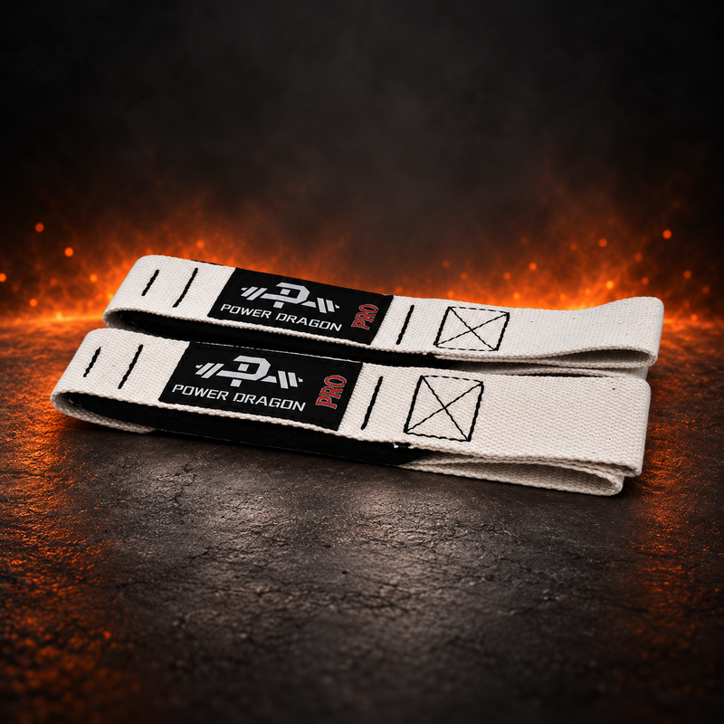 Lifting straps in off-white canvas with black barbell-logo labels, folded pair on a dark background.