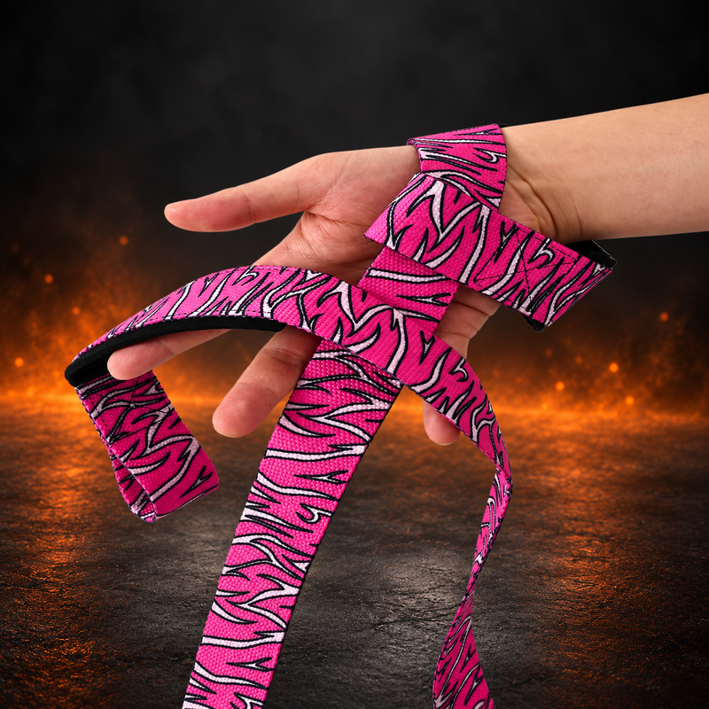 Arashi lifting straps looped around a lifter's wrist, hot pink webbing slashed with white strokes outlined in black