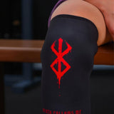 Berserk anime knee sleeve with brand of sacrifice symbol and text on a person's knee, blurred background