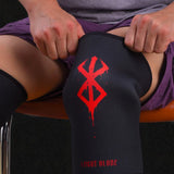Person wearing Berserk knee sleeves, sitting on an orange stool.