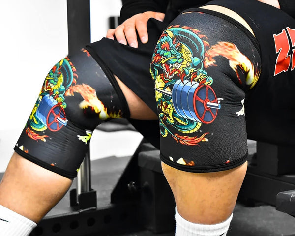 Person wearing black knee sleeves with colourful dragon artwork.