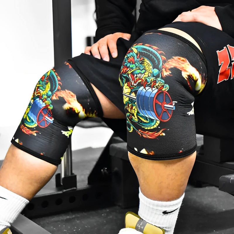 Person wearing black knee sleeves with colourful dragon artwork.