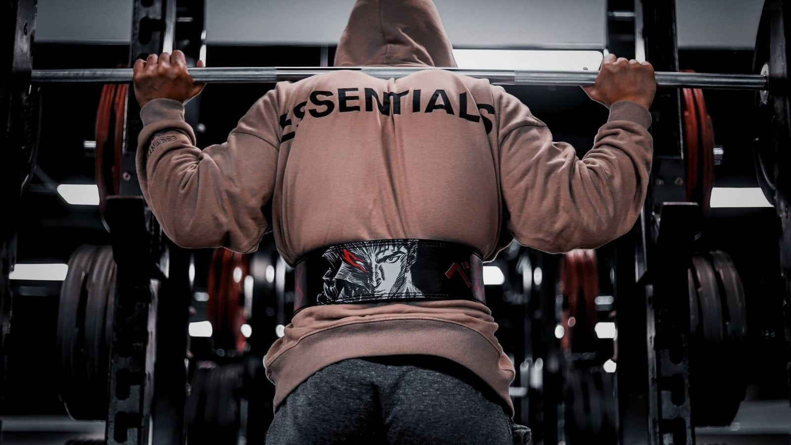 Powerlifting model in hoodie wearing berserk anime lever belt in the gym