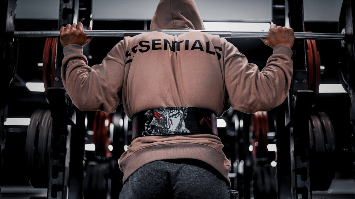 Powerlifting model in hoodie wearing berserk anime lever belt in the gym