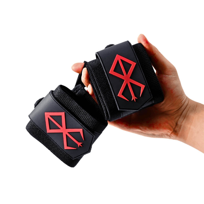 Hand holding the Sigil wrist wraps, a black pair with a raised red sigil on each closure tab