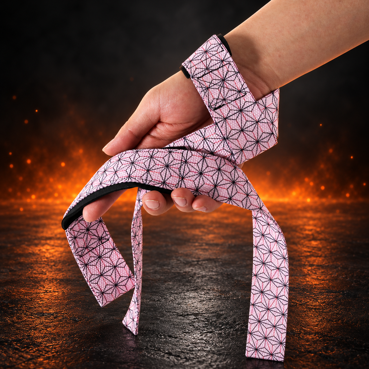 Wrist view of the Asanoha lifting straps looped over the hand, pale pink webbing with black six-point hemp-leaf stars
