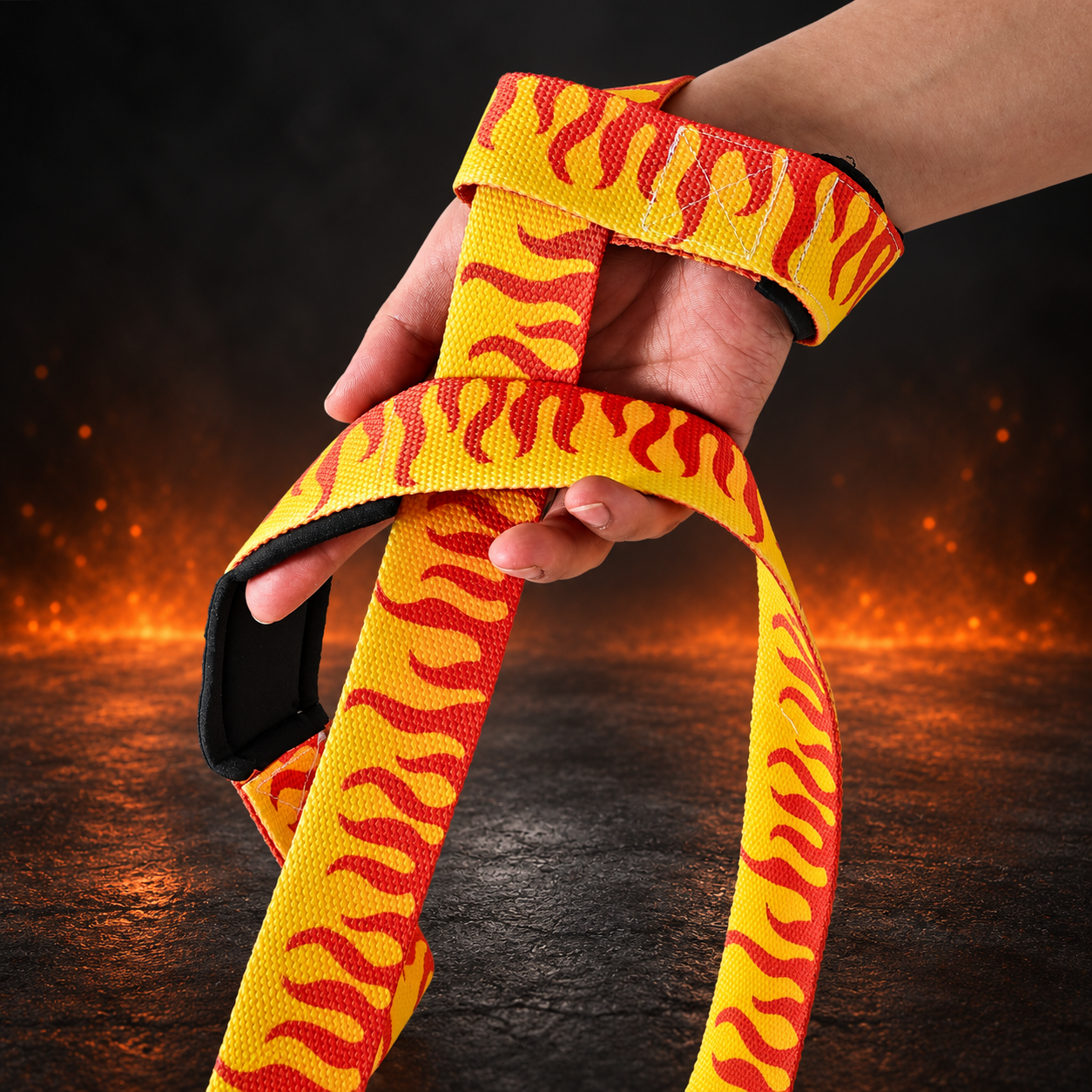 Wrist view of the Kaen lifting straps, red-orange flames on yellow webbing with black padding under the palm