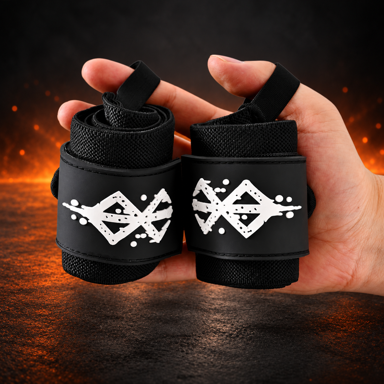 Rolled pair of Warrior wrist wraps held in one hand, all black with a distressed white sigil on each closure panel