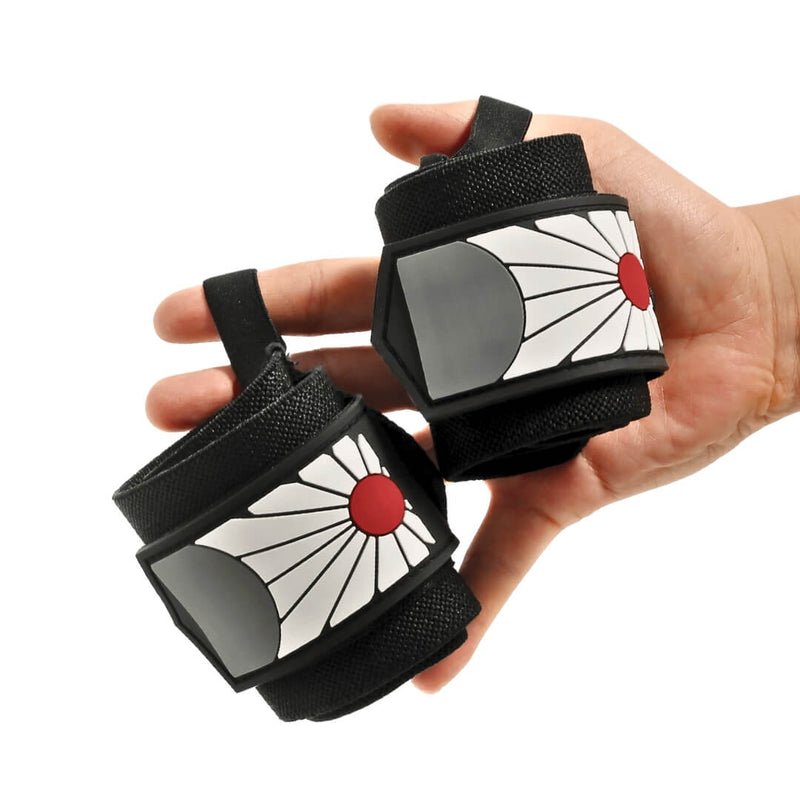 Pair of Hanafuda wrist wraps held in one hand, rolled black wraps with a red sun and white rays on each end tab