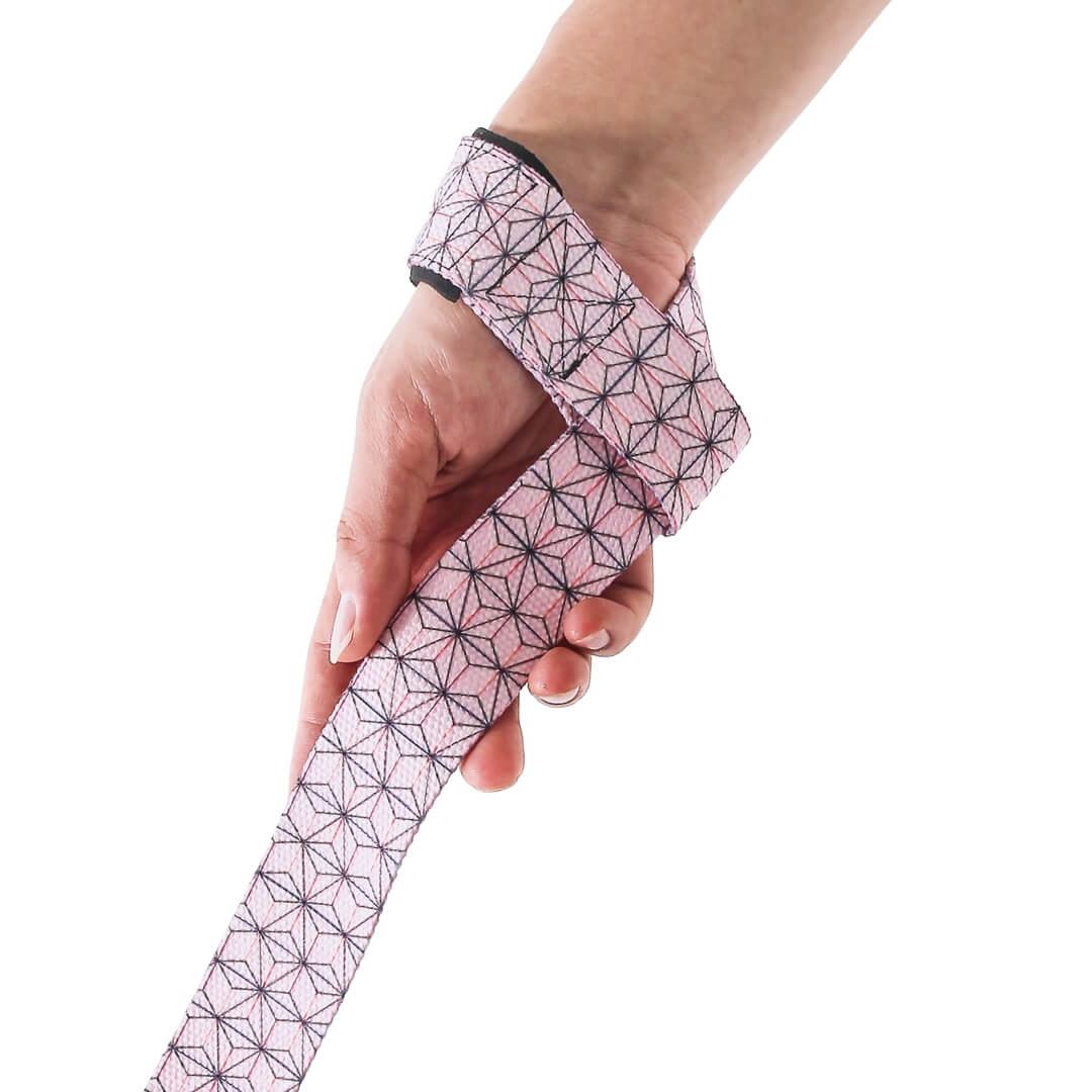 Side view of the Asanoha Edo weightlifting straps, a pink strap printed with a hemp leaf pattern hanging from the wrist