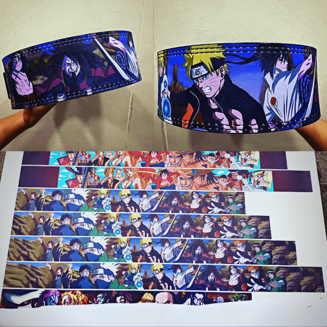 Custom powerlifting lever belts with full-color character art held up in hand, above printed belt strips before cutting.