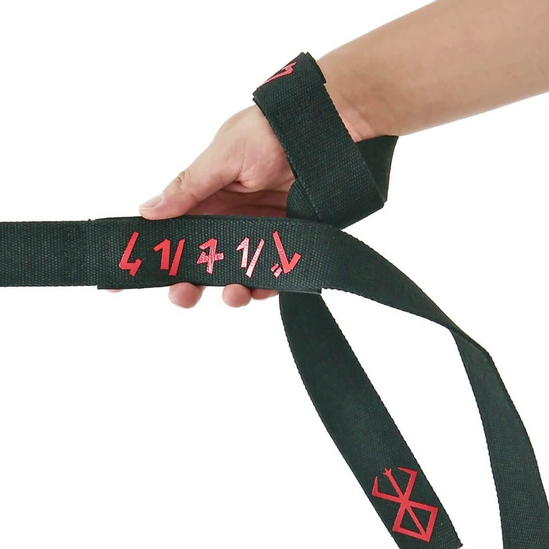 Lifting straps in black, looped on the wrist with the red-script pad held in the hand.
