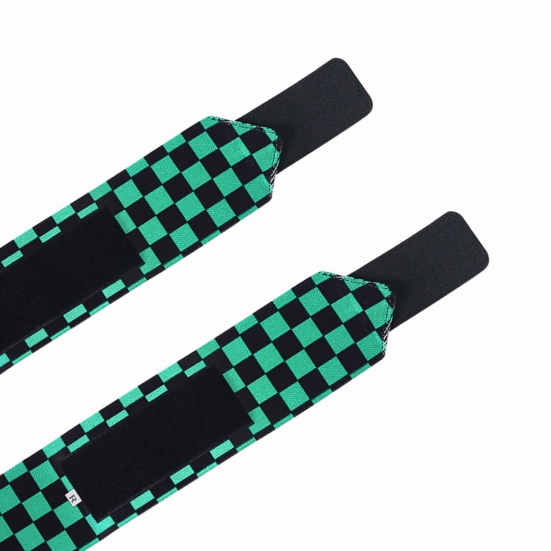 Powerlifting wrist wraps in green and black checkerboard with black closure tabs, tail ends close-up.