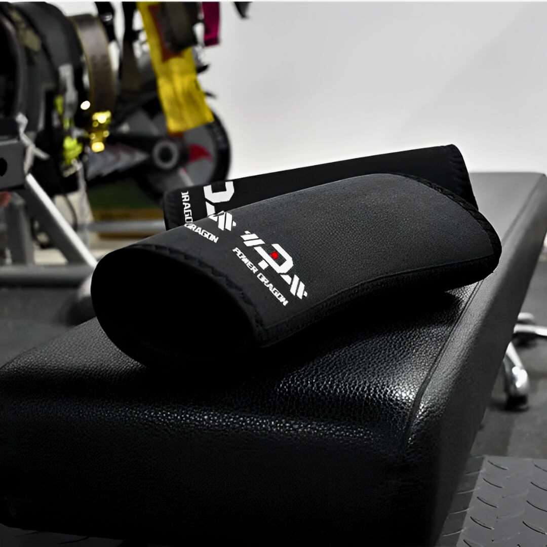 7mm stiff knee sleeves in black with white barbell logos, pair lying stacked on a gym bench.