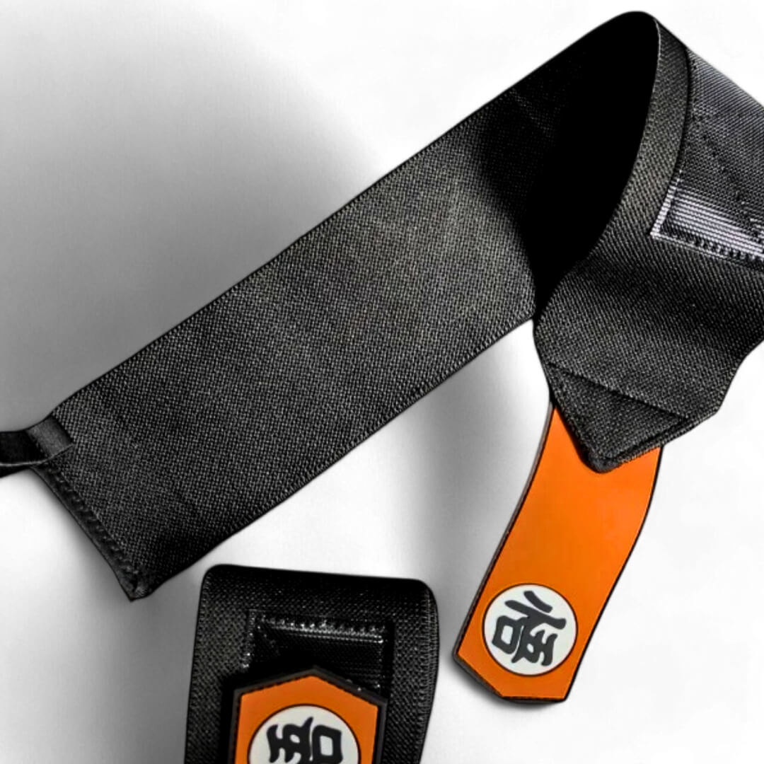 Powerlifting wrist wraps, one unrolled to show the long black wrap and pointed orange kanji tab.