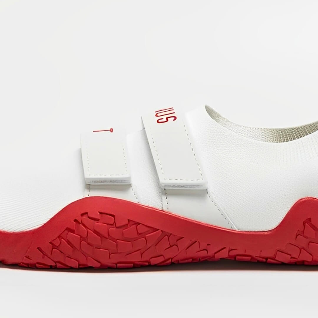 Deadlift slippers in white, close-up of the straps, red lettering and red textured sole.