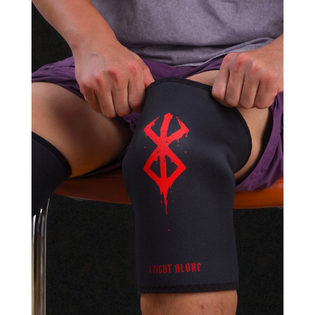 7mm stiff knee sleeves in black with a dripping red mark, pulled up by a seated athlete.